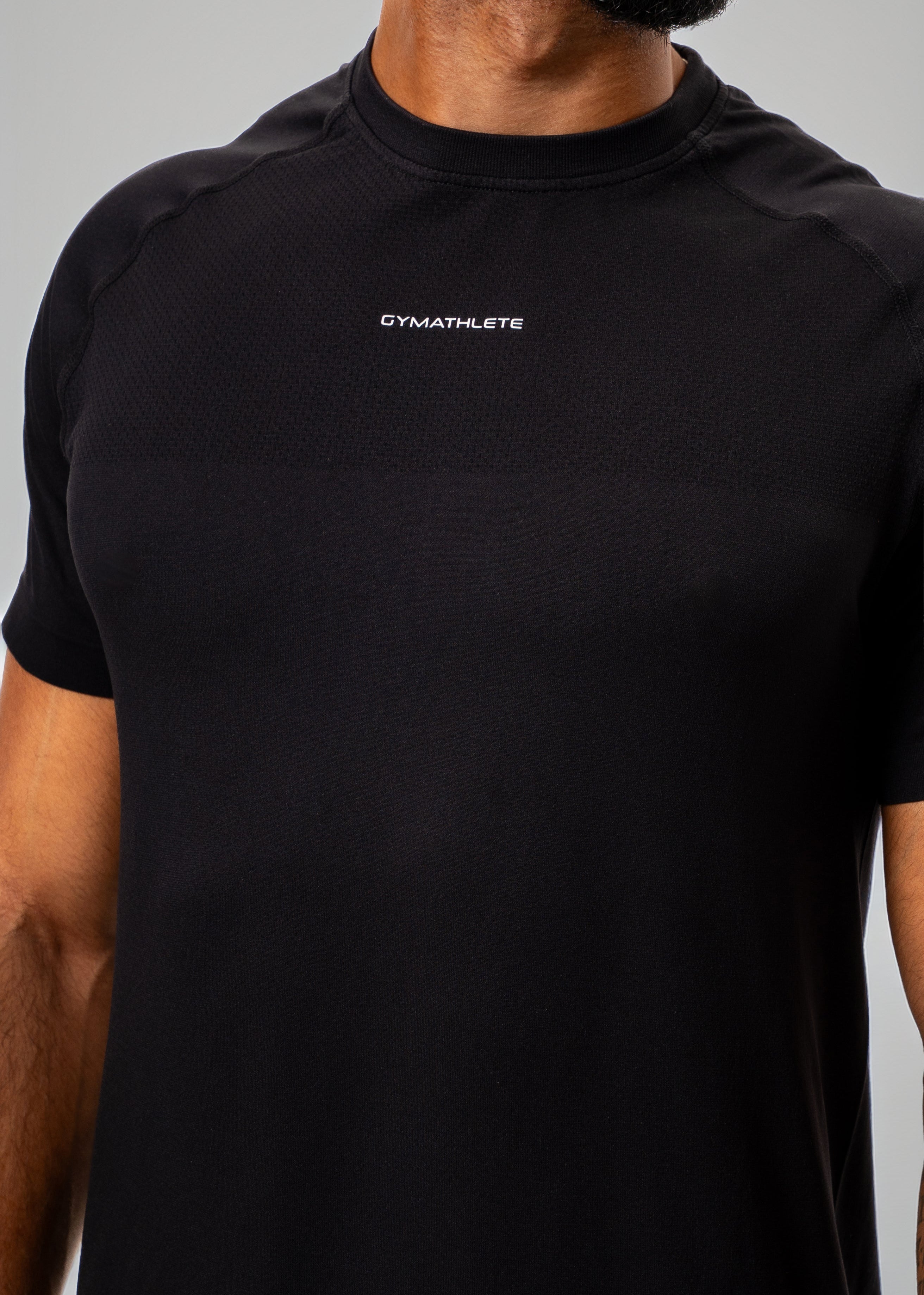 Man wearing a black t-shirt and shorts on a light gray background - Gymathlete Elevate T-shirt