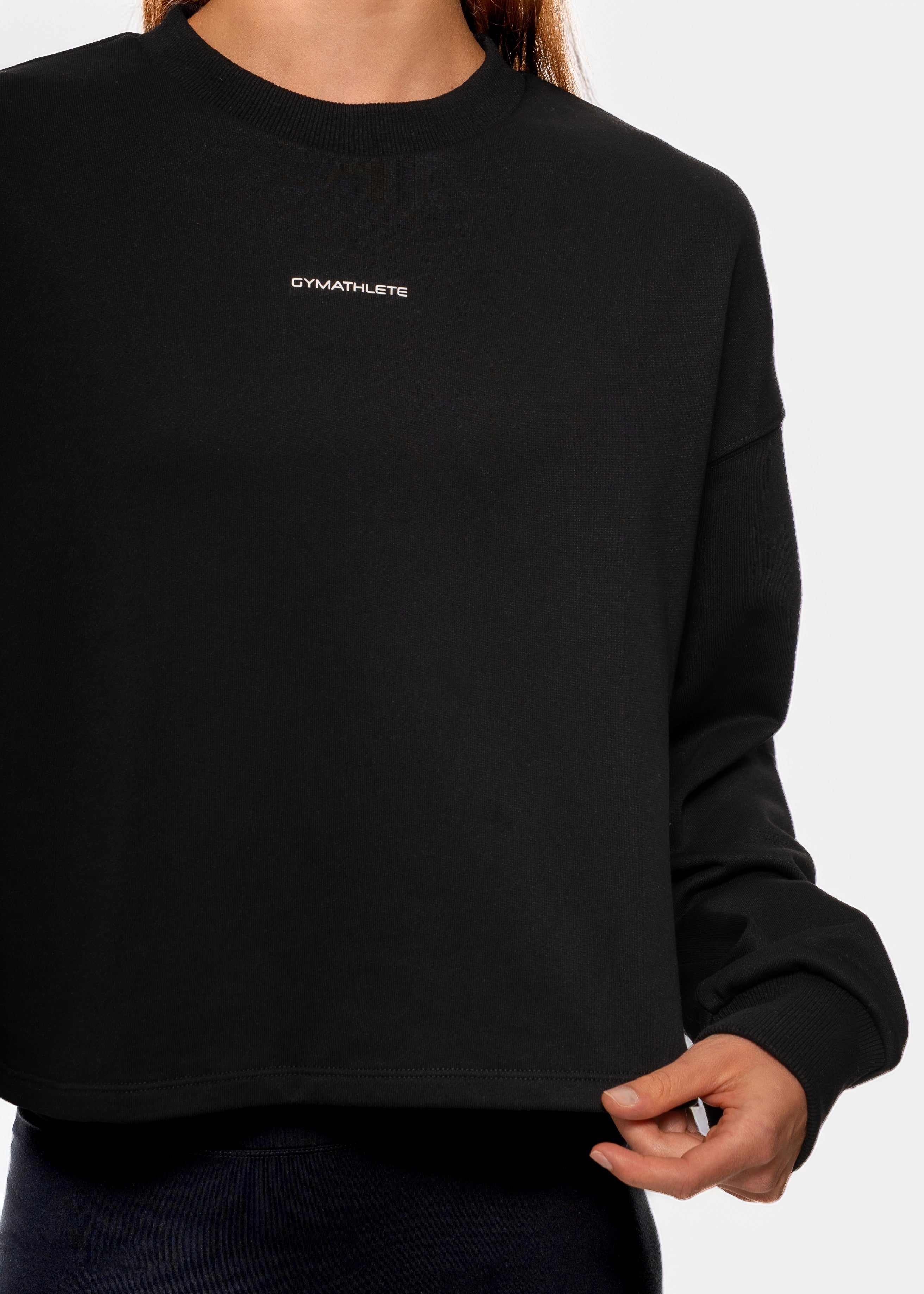 Black sweatshirt with 'GYMATHLETE' logo worn by a person on a white background. Flow crop sweatshirt