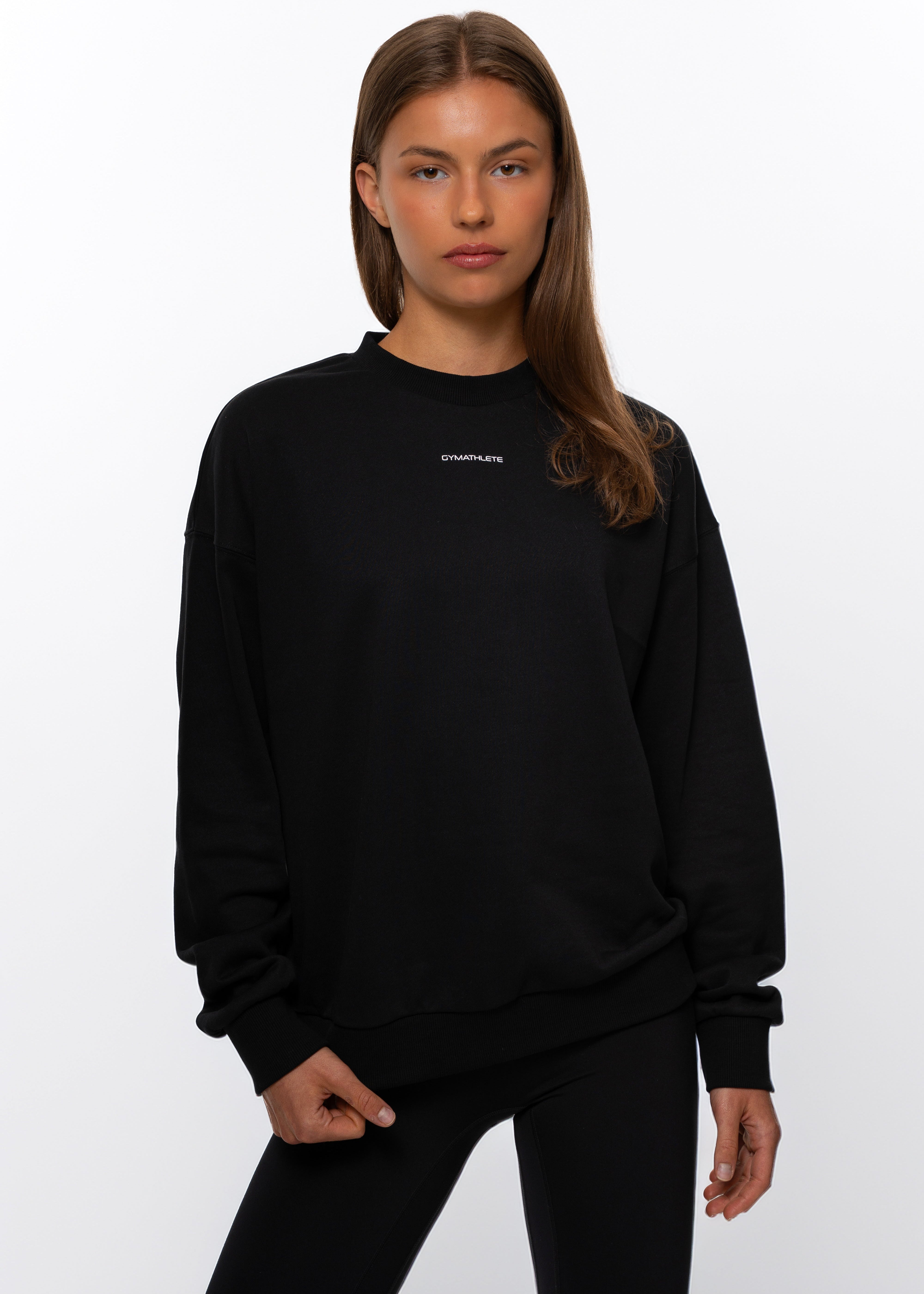 Person wearing a black sweatshirt with a logo on a white background. Women - Gymathlete - Flow Sweatshirt - Black.