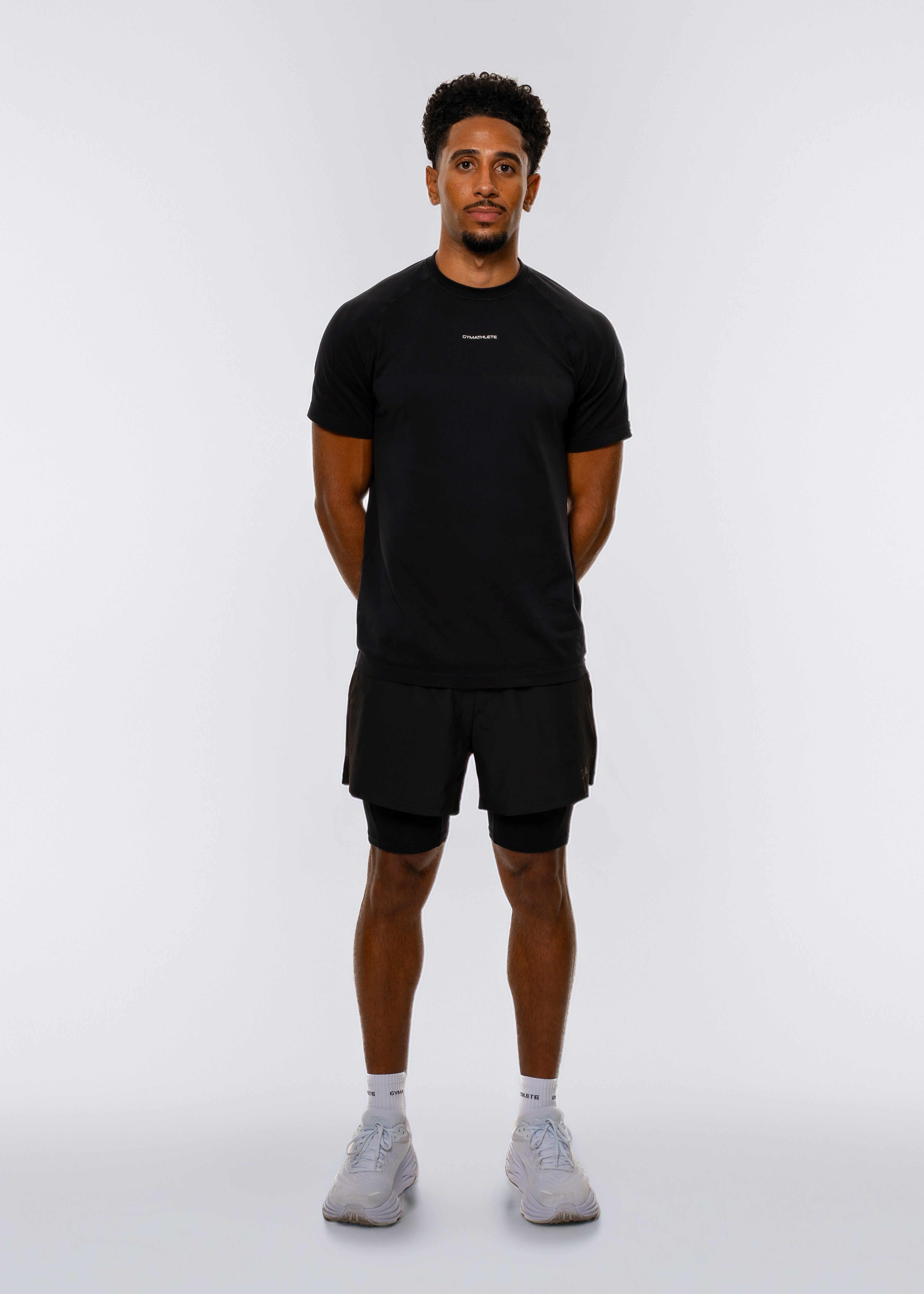 Man wearing a black t-shirt and shorts on a white background. Gymathlete - Elevate T-shirt - 2IN1 Shorts.