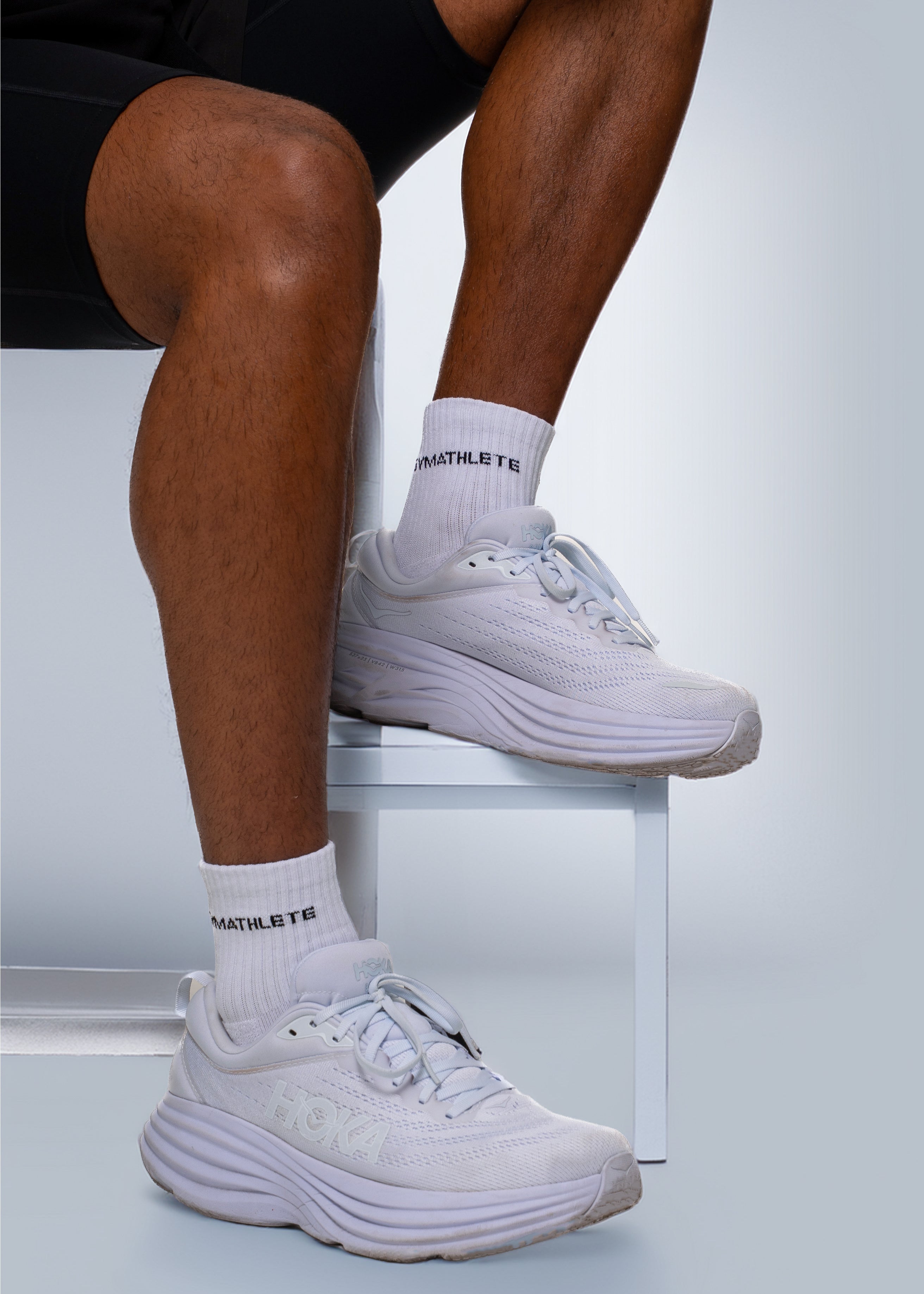 Person wearing white athletic shoes and socks on a light gray background - Gymathlete endurance socks