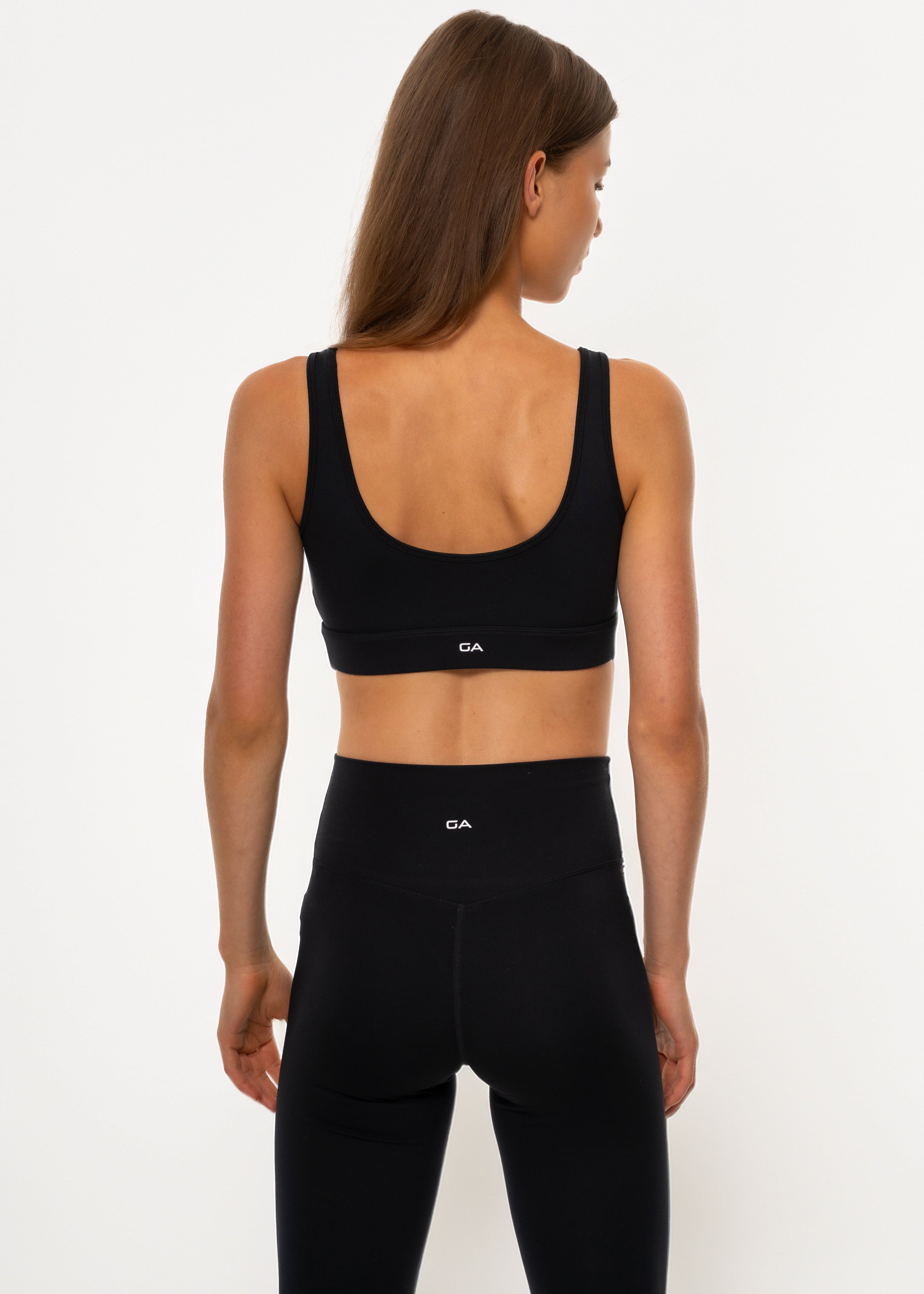 Person wearing a black sports bra and leggings on a white background. Pulse bra, gymathlete