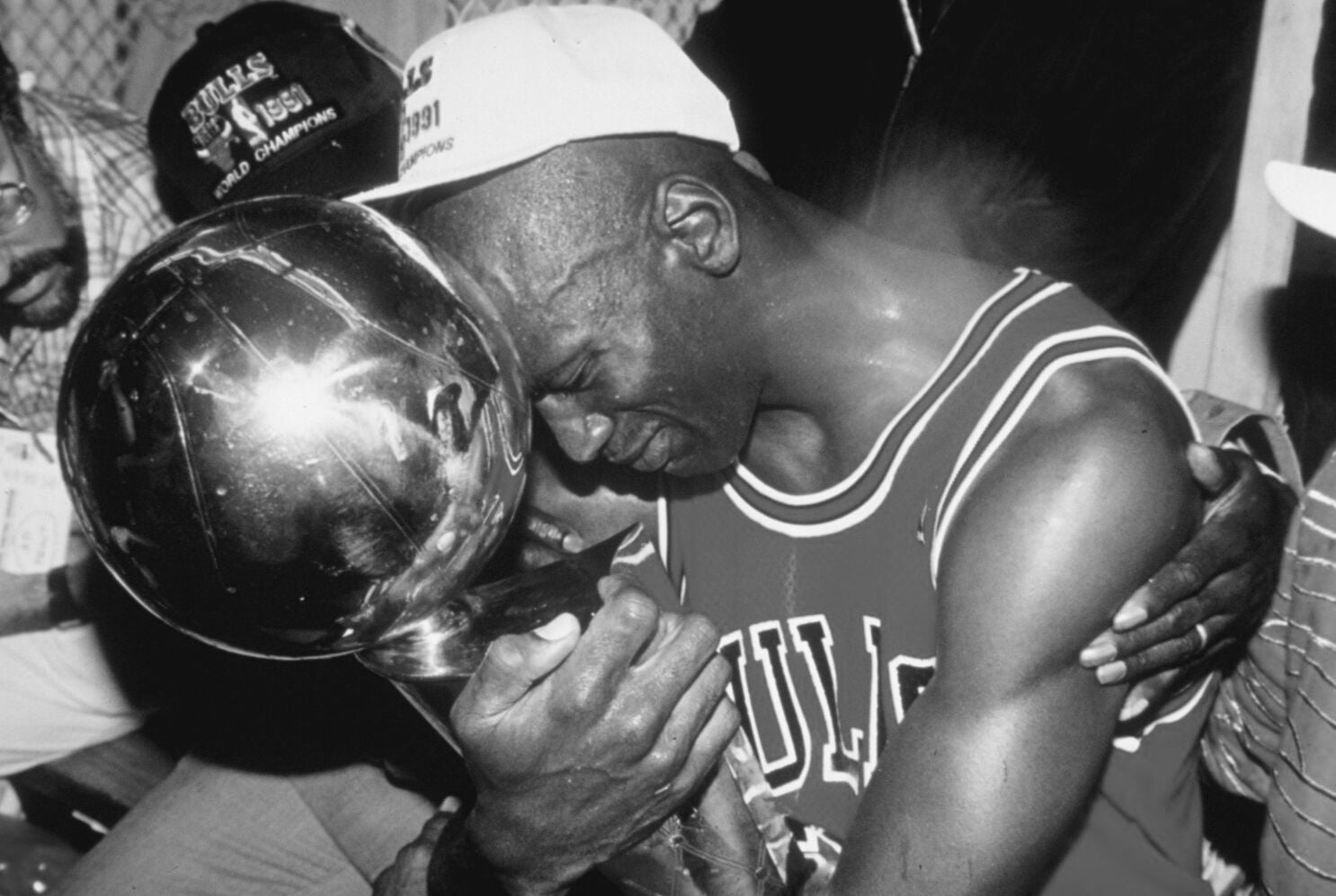 Black-and-white photo of a basketball player embracing a championship trophy—focus, discipline, quiet confidence. Gymathlete inspiration.