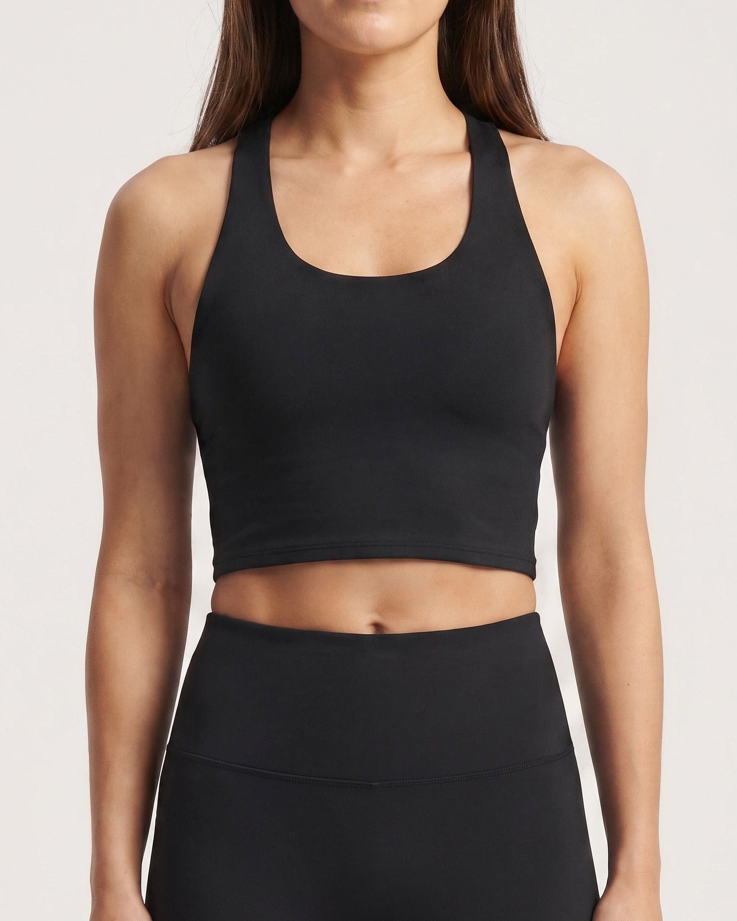 Woman wearing the Gymathlete Pulse Crop Top in black with matching high-waist leggings, front view
