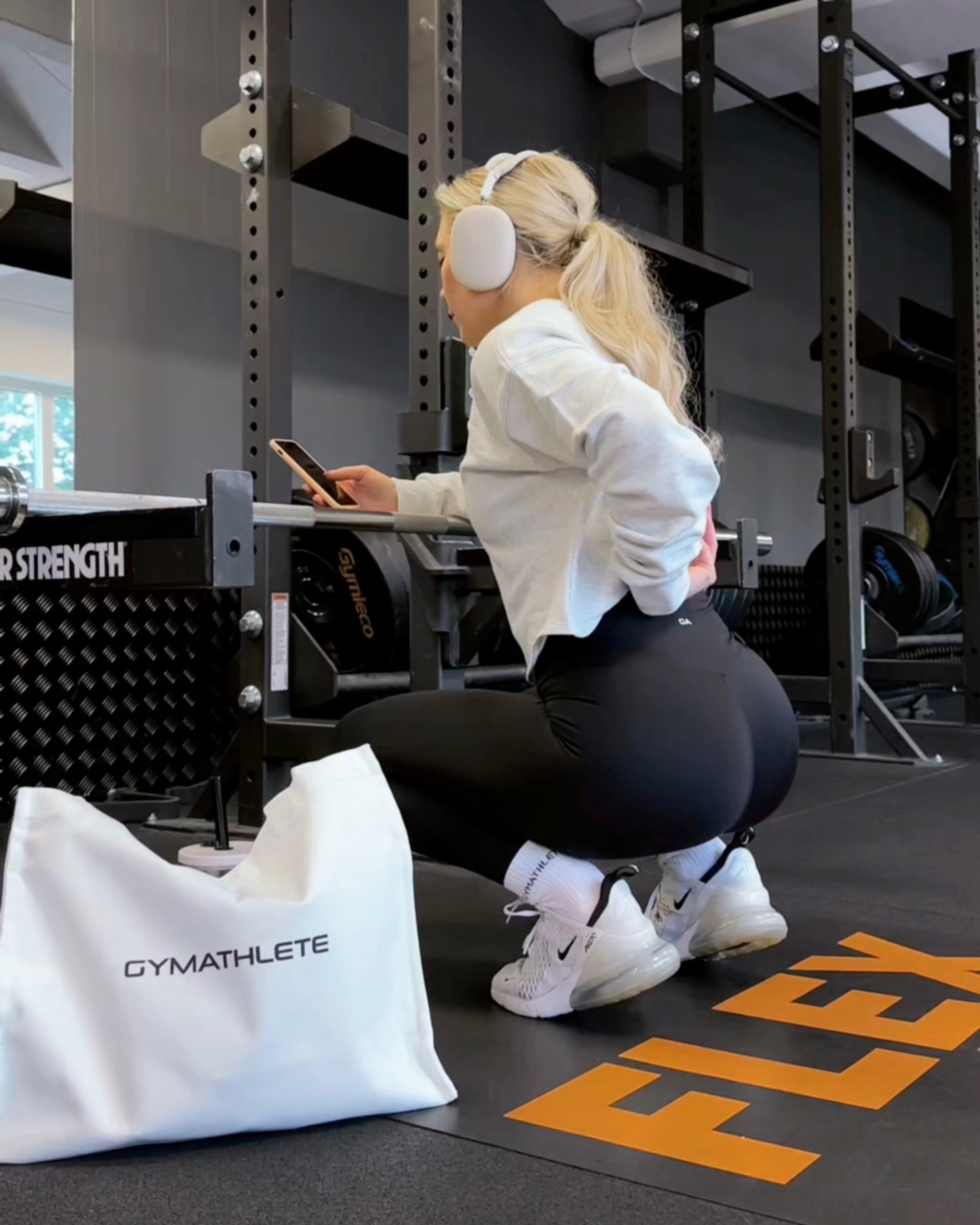 Woman wearing black squat-proof leggings in a gym by a barbell rack 