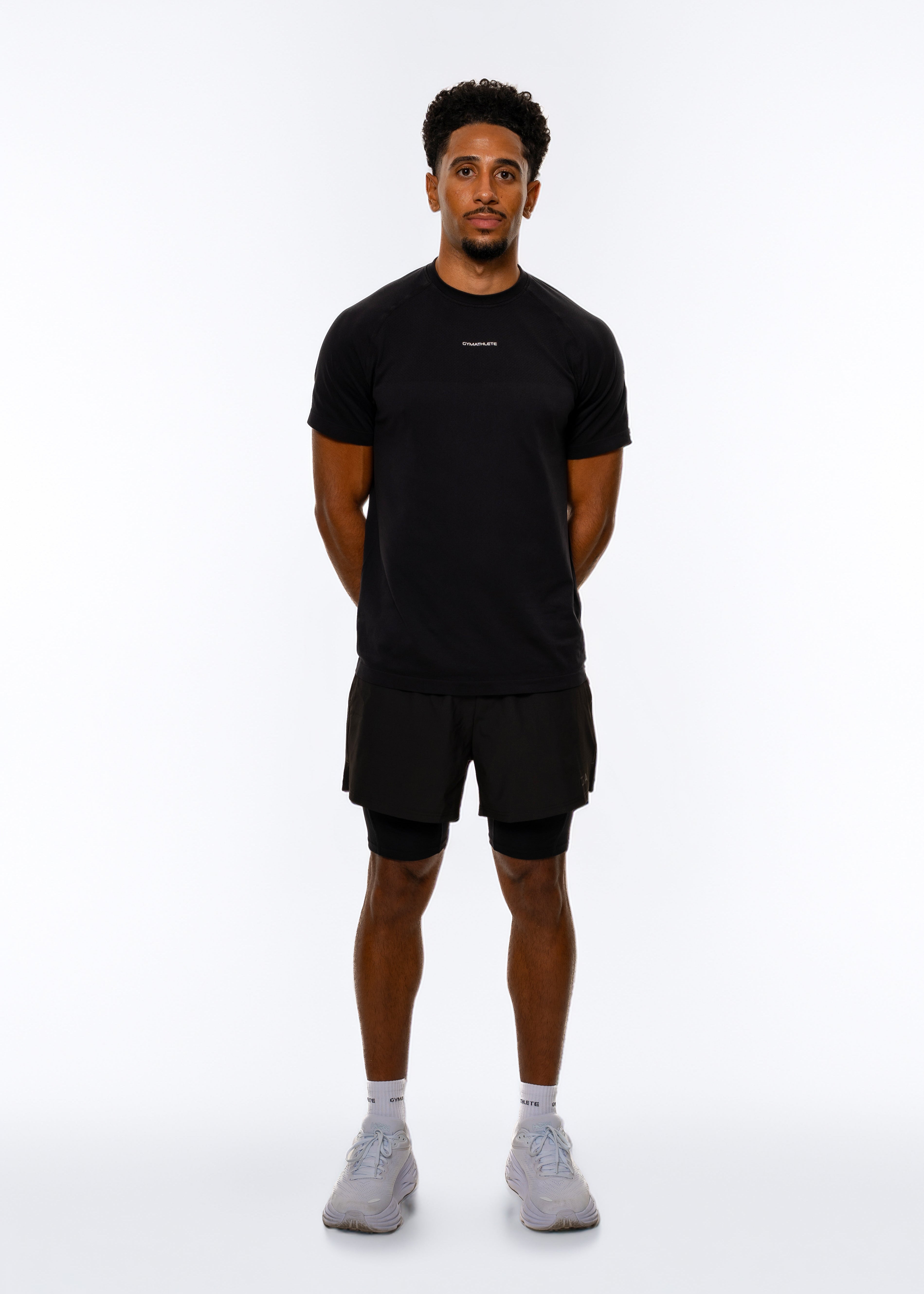 Man wearing a black t-shirt and shorts on a white background. Gymathlete Elevate T-shirt