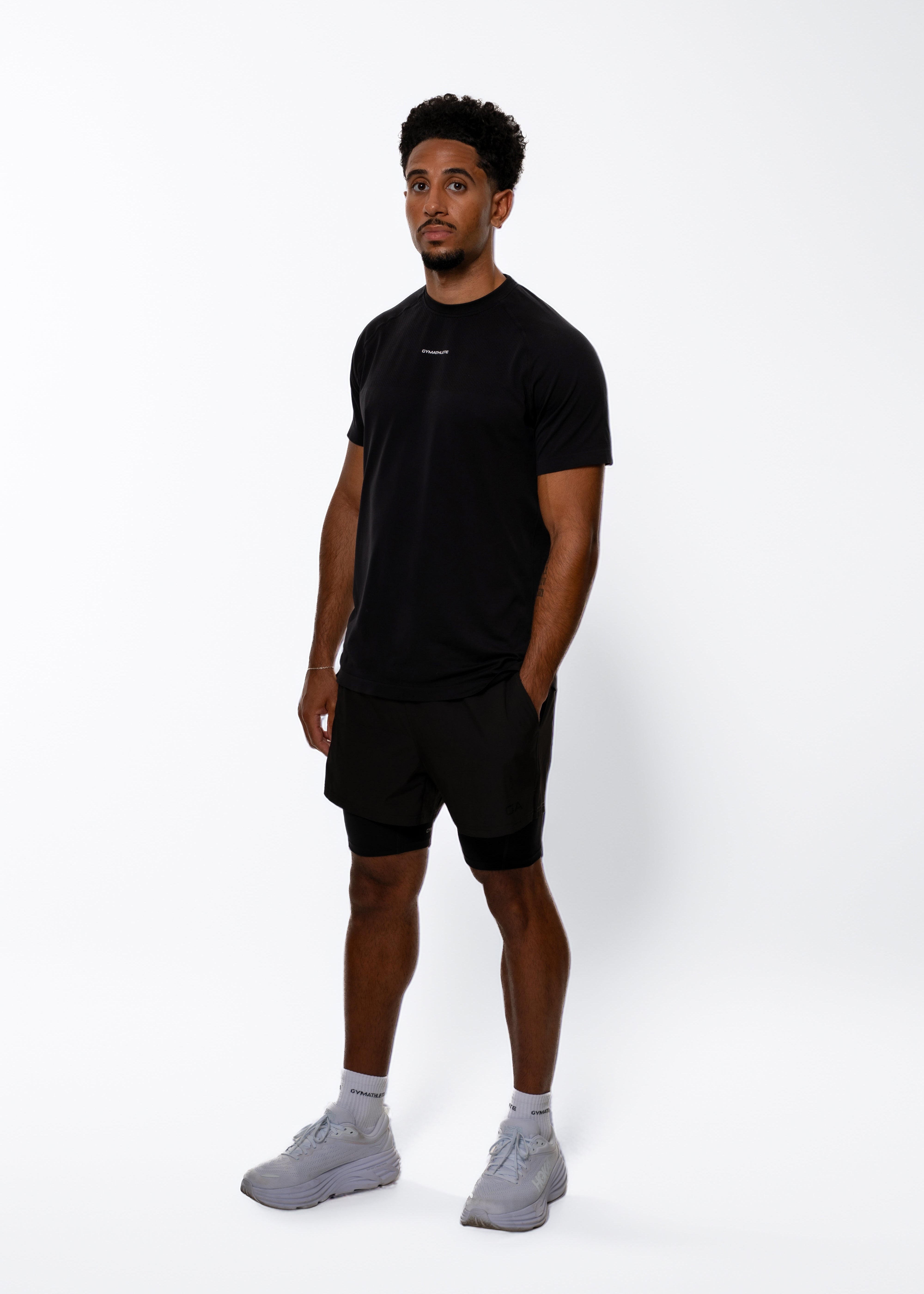 Man wearing a black t-shirt and shorts on a white background. Gymathlete, Elevate T-shirt