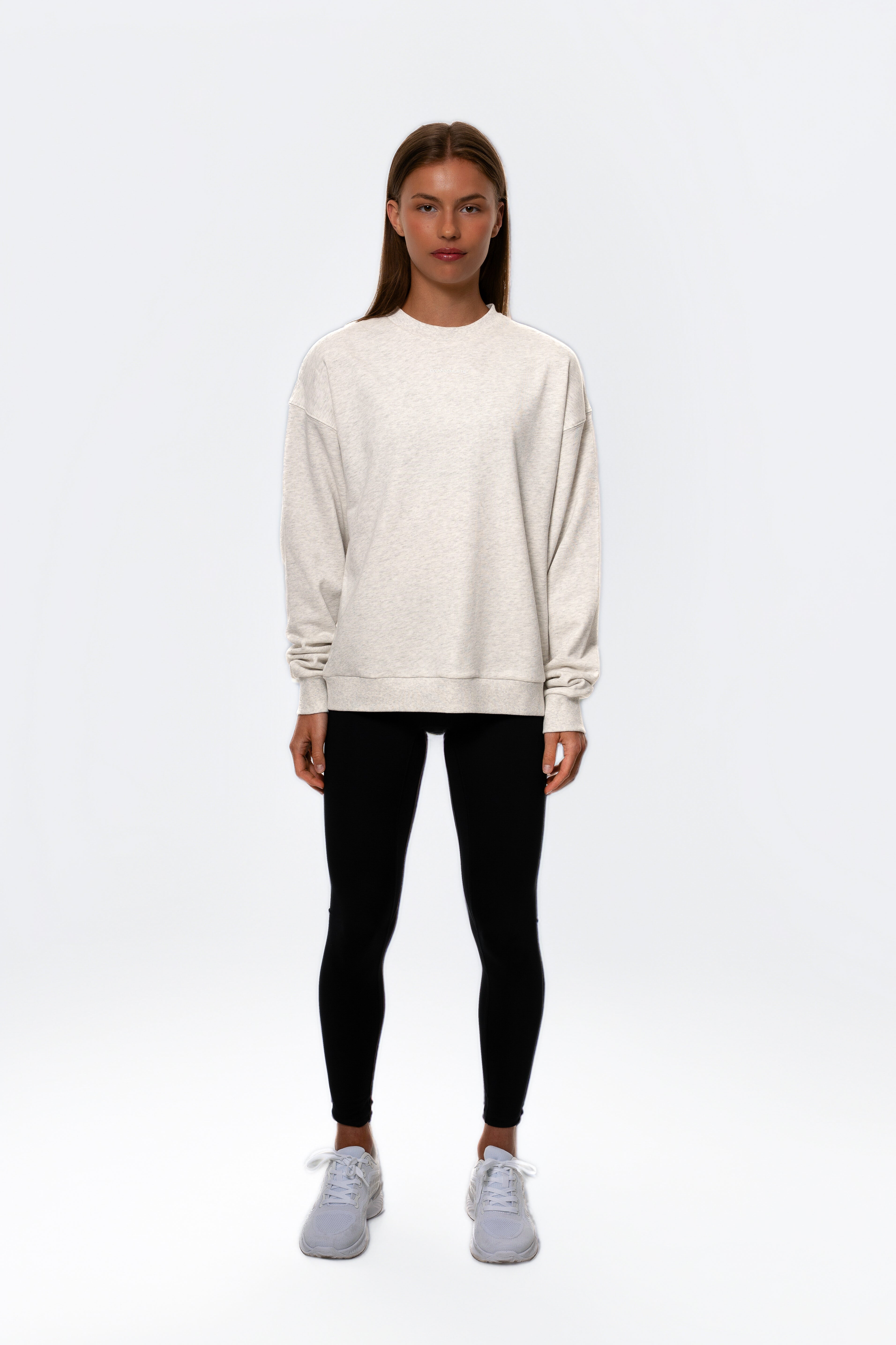 Person wearing a white sweatshirt, black leggings, and white sneakers on a white background. Women - Gymathlete - Flow Sweatshirt - White melange.