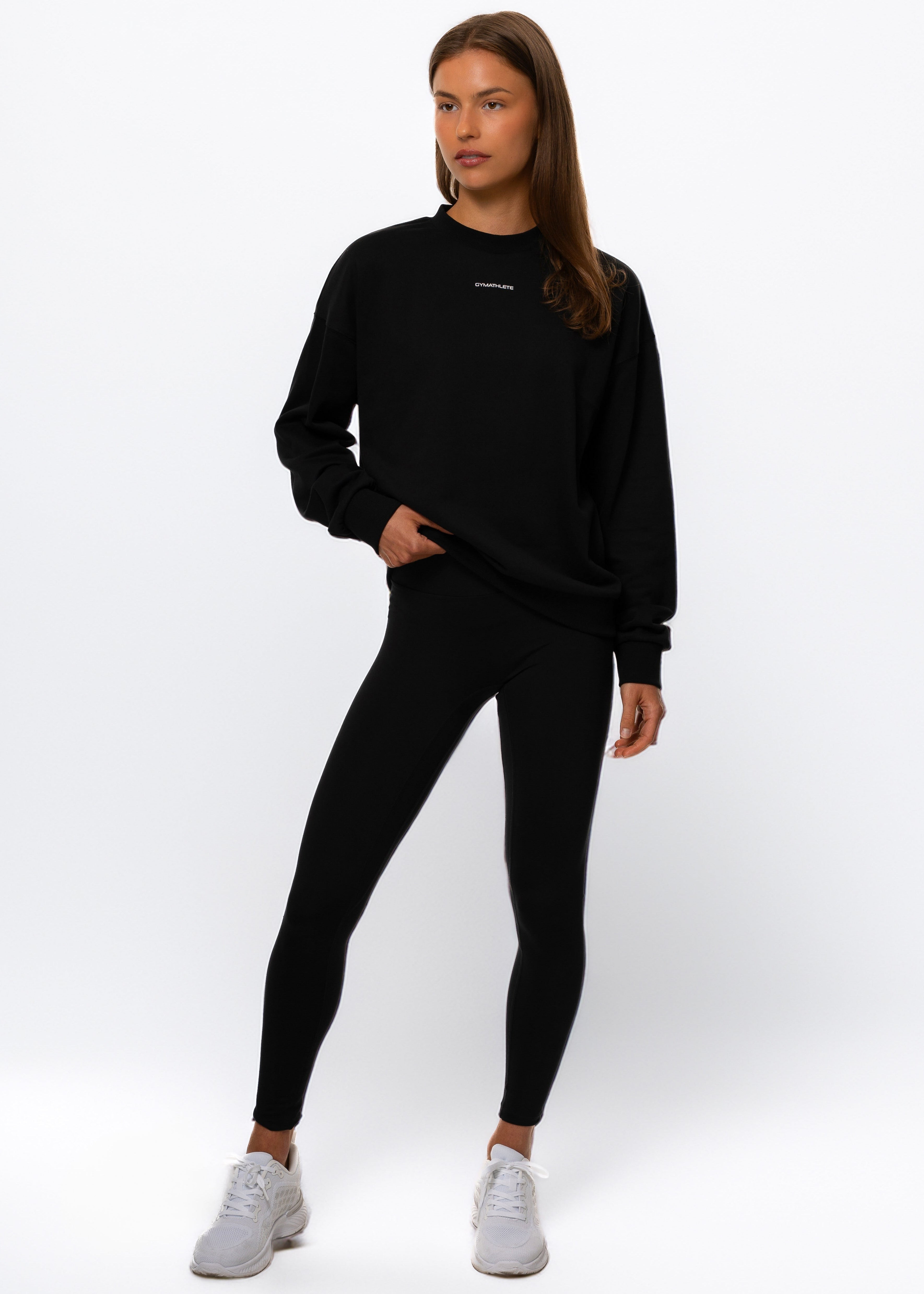 Woman wearing a black outfit with a visible brand logo on a white background. Women - Gymathlete - Flow Sweatshirt - Black.