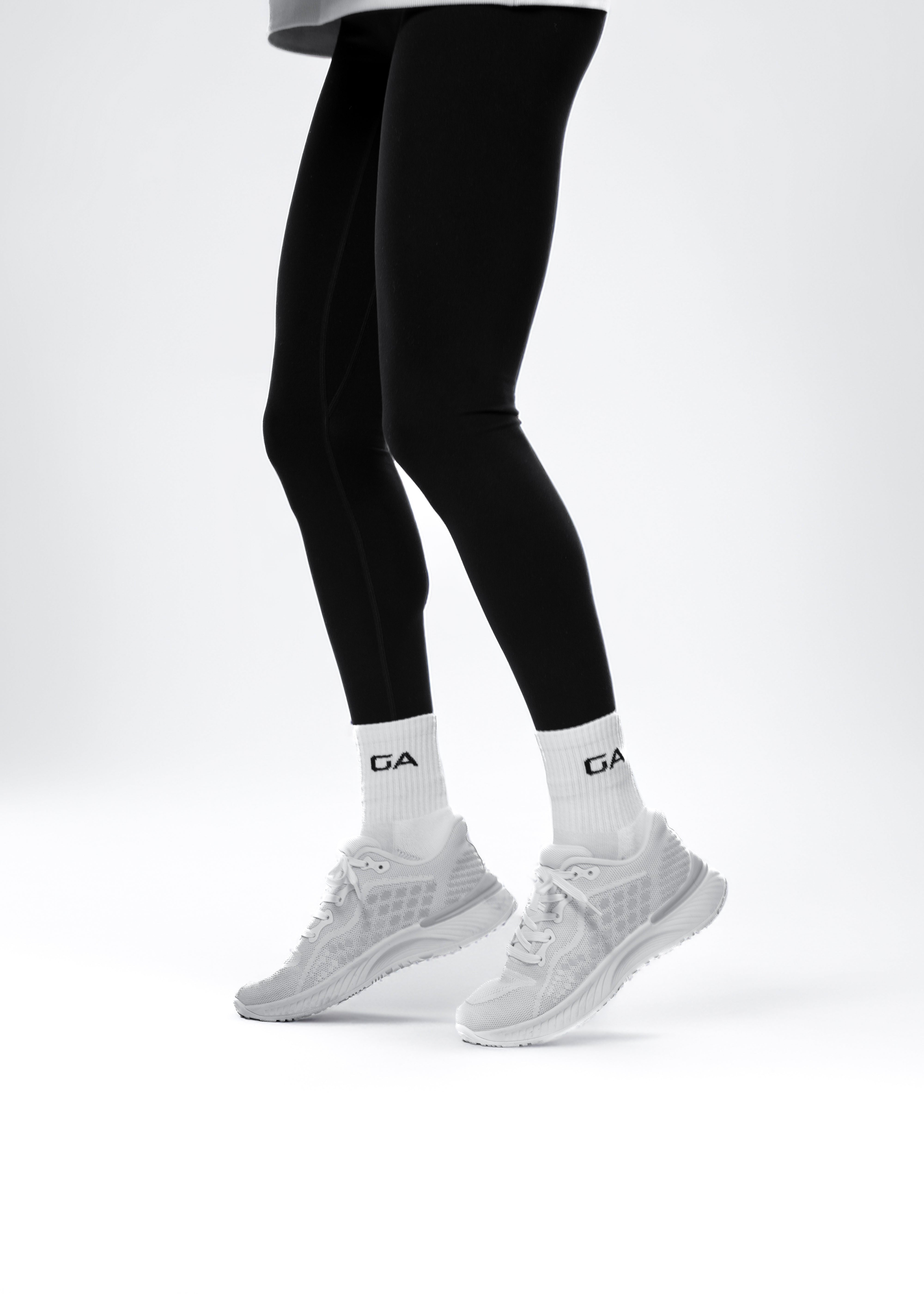 Person wearing black leggings, white socks, and gray athletic shoes on a white background. Gymathlete Endurance socks - women