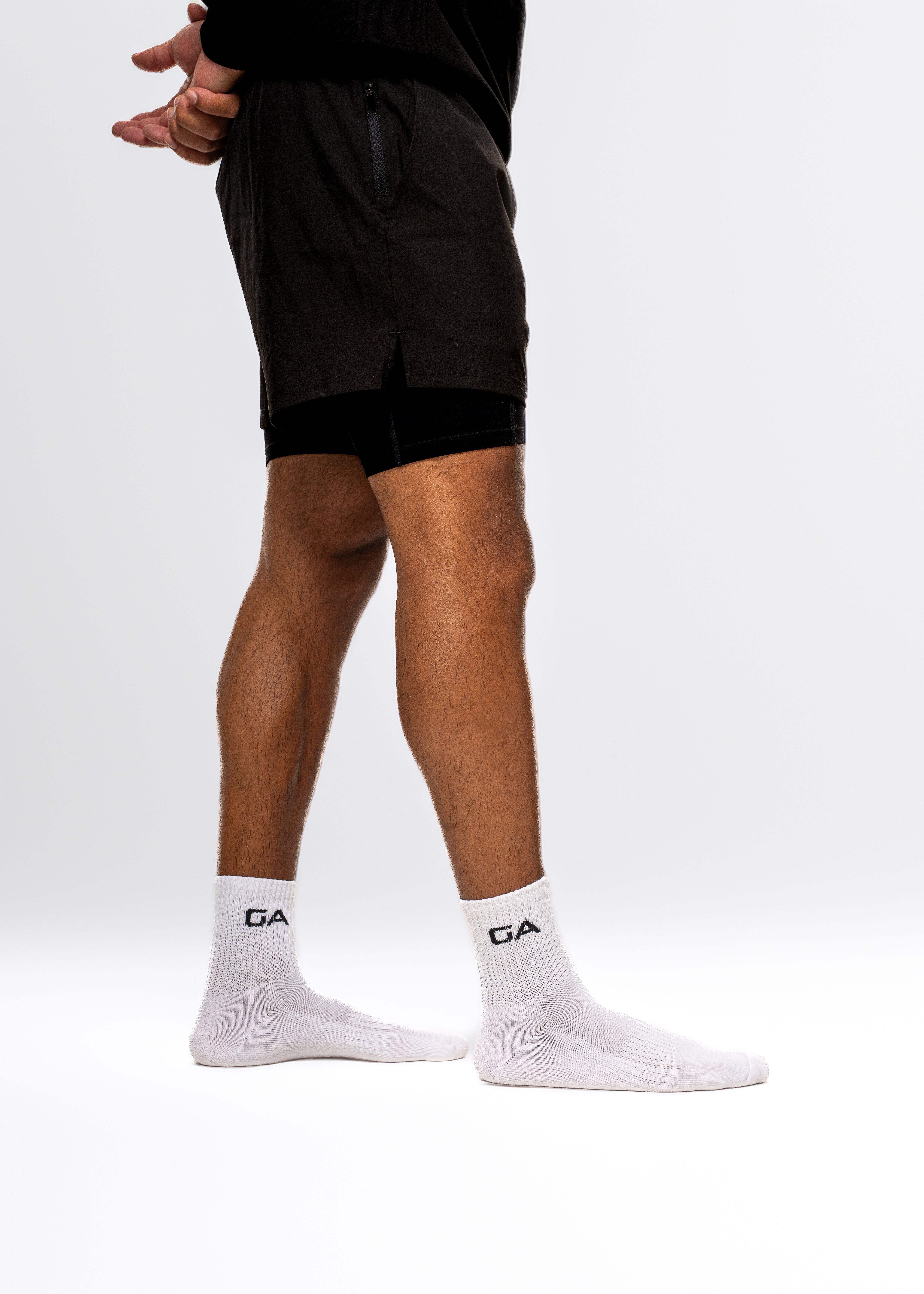 Person wearing black shorts and white socks with a brand logo on a white background. Gymathlete - GA Endurance socks