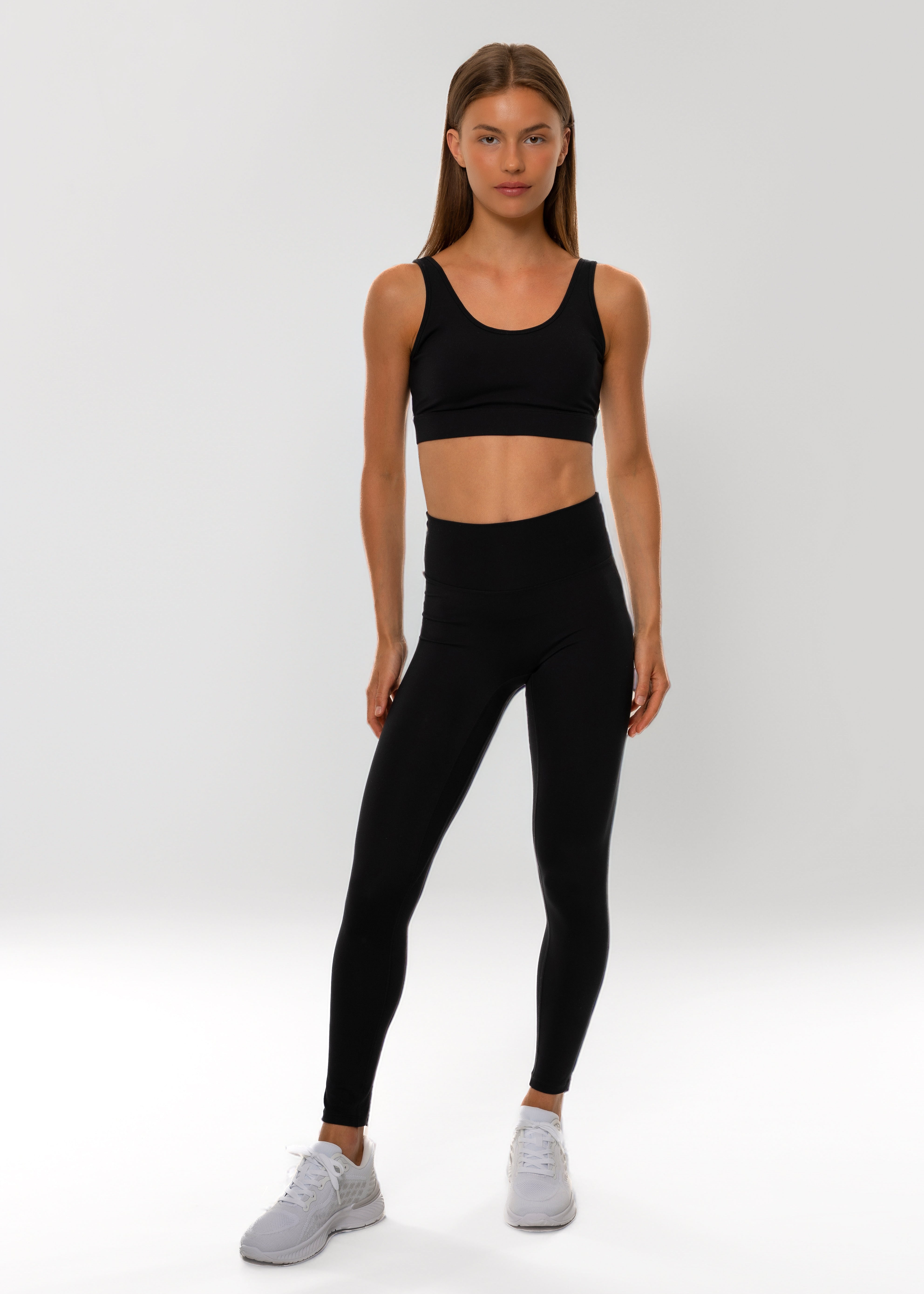 Person wearing a black athletic outfit on a white background. Pulse bra gymathlete
